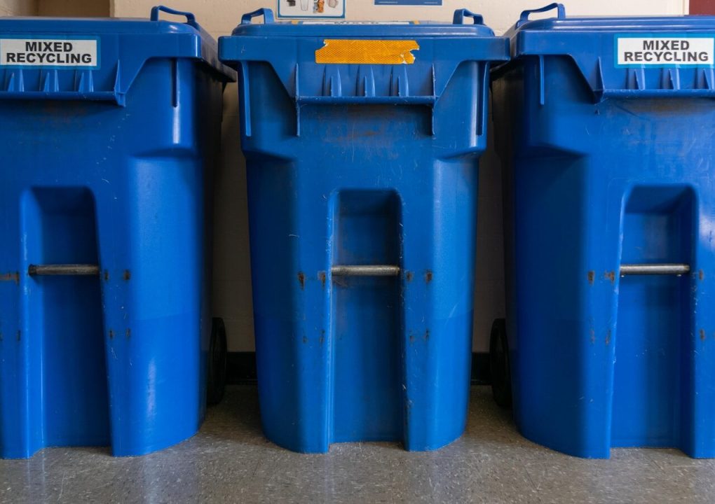 a couple of blue trash cans sitting next to each other